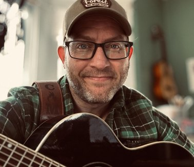 Campfire Junkie holding an acoustic guitar